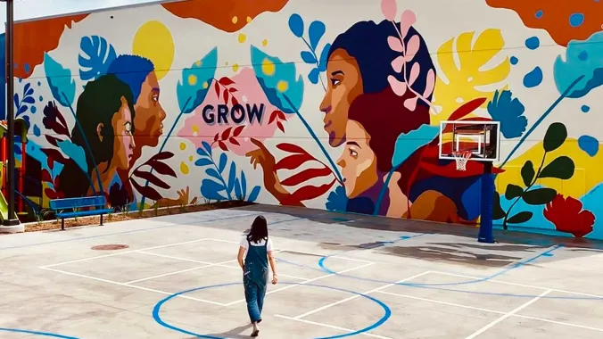 person standing in front of a colorful mural 