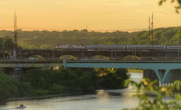 A roadway and an Amtrak train during golden hour.