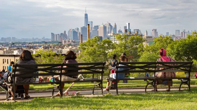 people sitting on a bench overlooking new york skyline