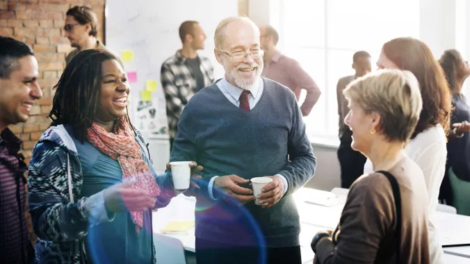 Five people talking and laughing in an office