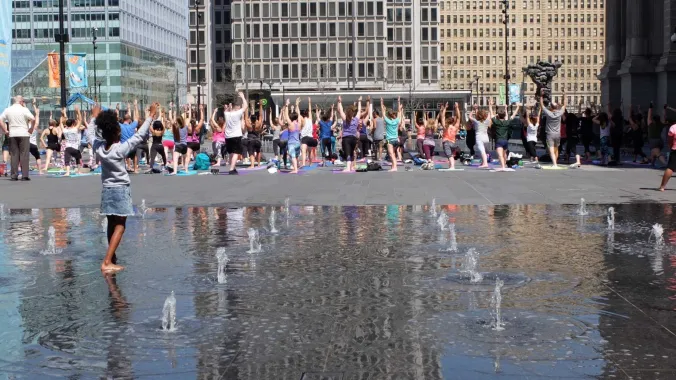 large group of people doing yoga outdoors in a city center