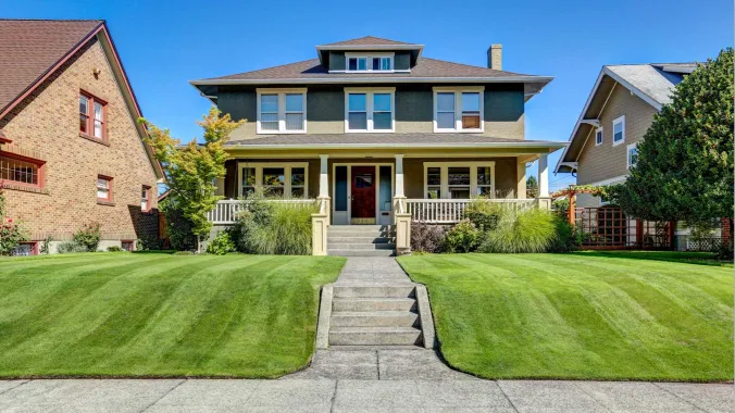 two-story craftsman style home with a green lawn 