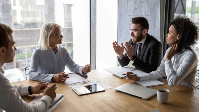 four people in business attire meeting around conference table