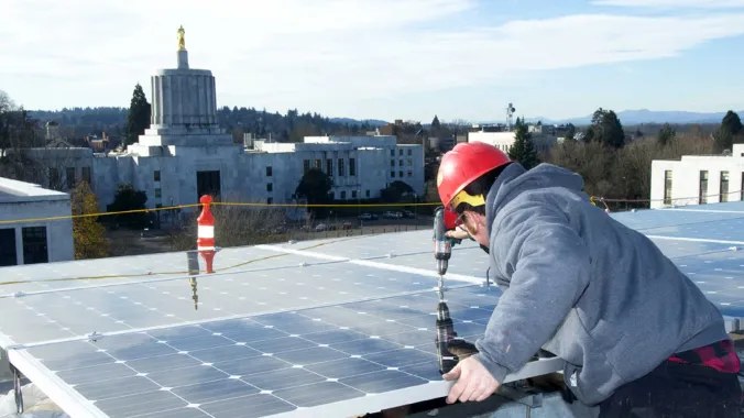 person installing solar panels on building roof