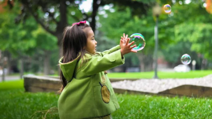 child playing with bubbles in park