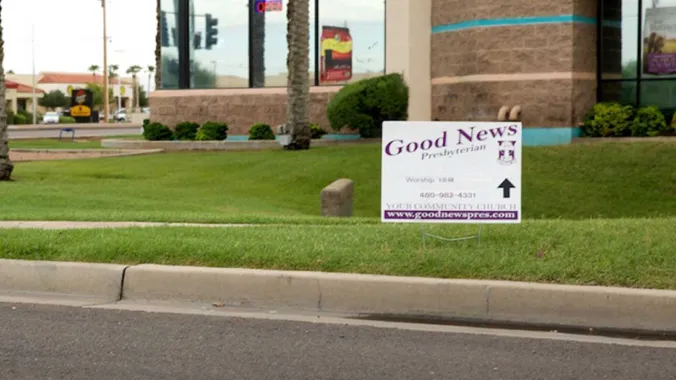 sign placed in grass next to street