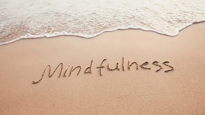 Mindfulness written in sand at beach