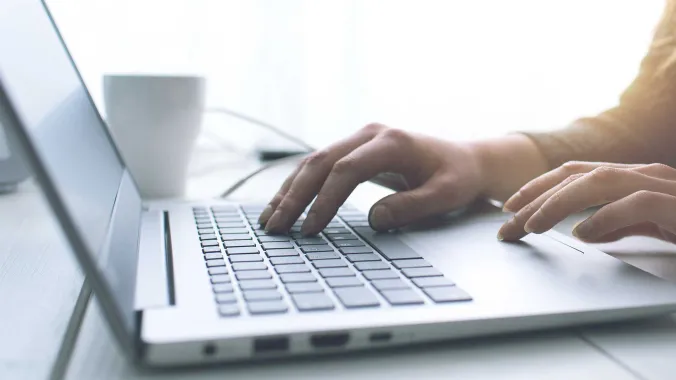 closeup of hands typing on laptop