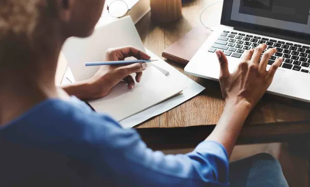woman writing and typing on laptop