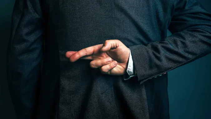 man in suit with fingers crossed behind their back