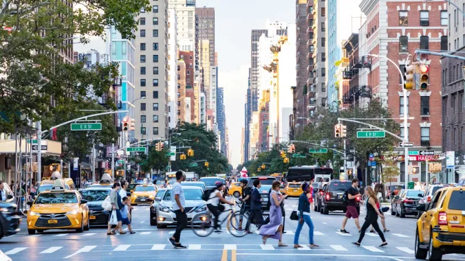 people crossing a busy intersection with new york buildings in the background