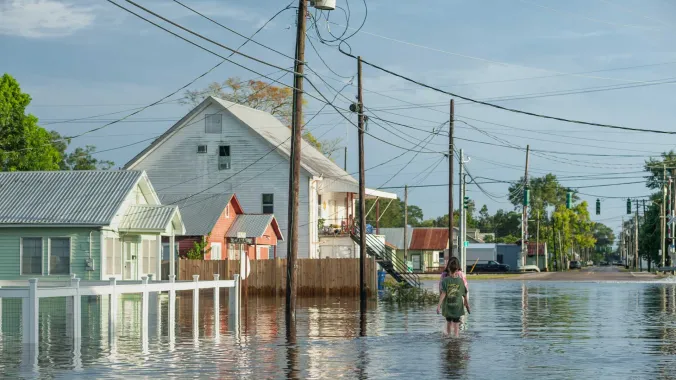 two people walking in a flooded street with houses