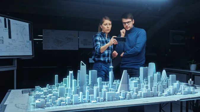 Enhancing Public Participation with Generative AI course image of two people standing over a blue city diagram with the women holding up a cell phone