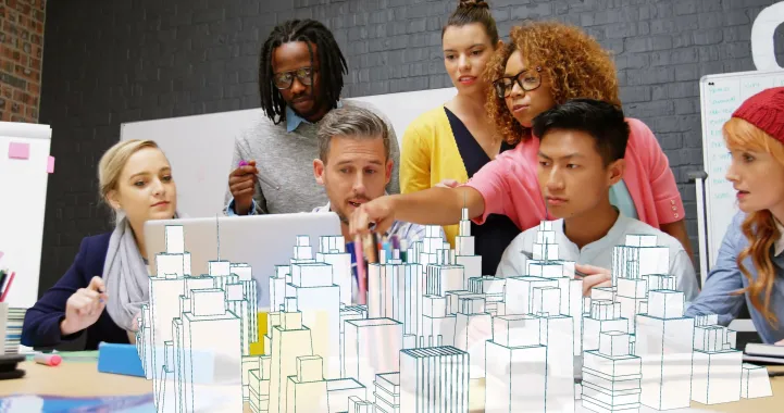 Image of people gathered together lookin at a computer screen with an opec image of buildings in front of them