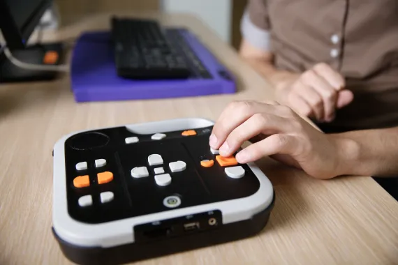 Person using a device to assist with listening to things online through audio, typically used for the blind
