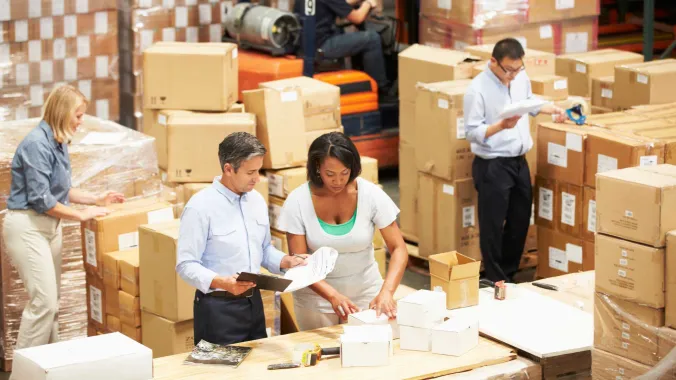 people working in a warehouse surrounded with boxes