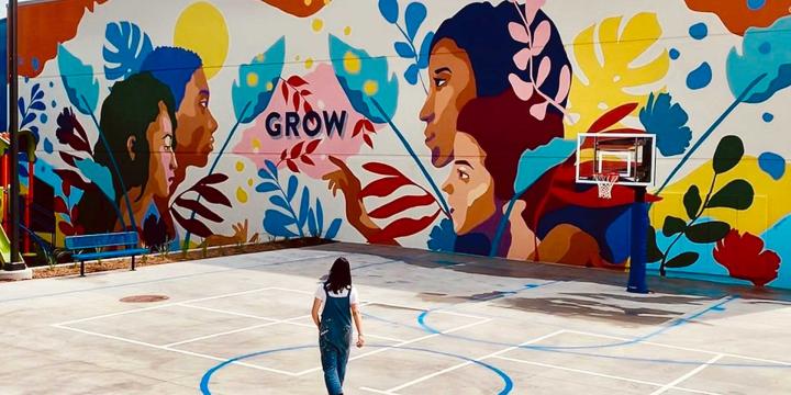 person standing in front of a colorful mural 