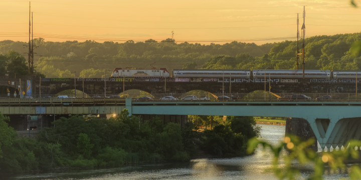 A roadway and an Amtrak train during golden hour.