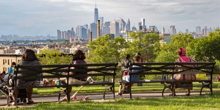 people sitting on a bench overlooking new york skyline