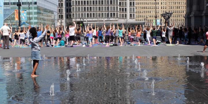 large group of people doing yoga outdoors in a city center