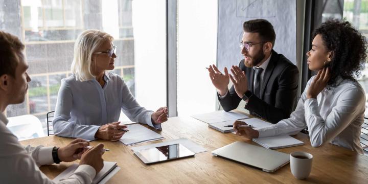 four people in business attire meeting around conference table