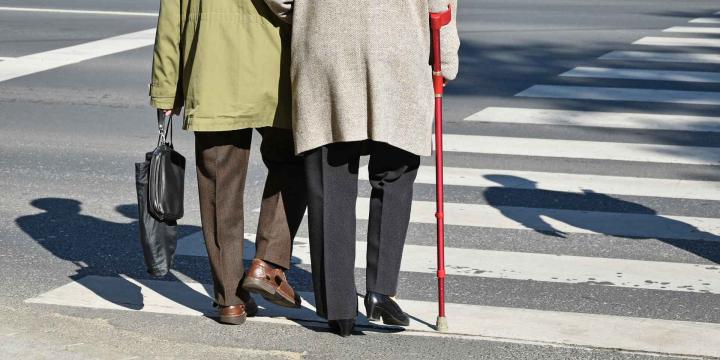 two elderly people crossing the street