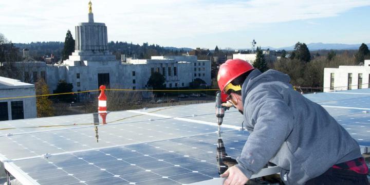 person installing solar panels on building roof