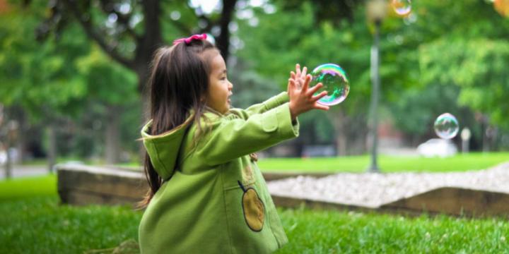 child playing with bubbles in park