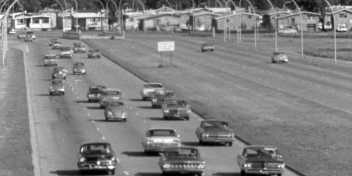 cars on highway with suburb in background