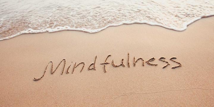 Mindfulness written in sand at beach