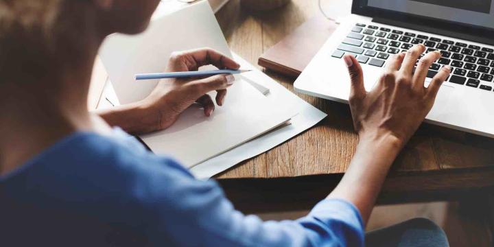 woman writing and typing on laptop