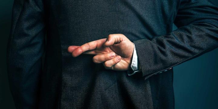 man in suit with fingers crossed behind their back