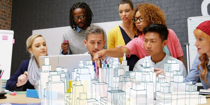 Image of people gathered together lookin at a computer screen with an opec image of buildings in front of them