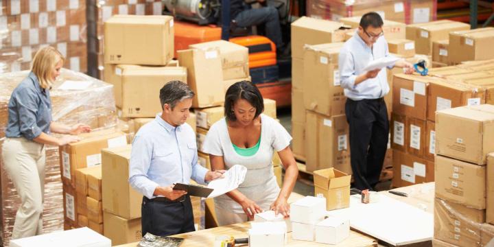 people working in a warehouse surrounded with boxes